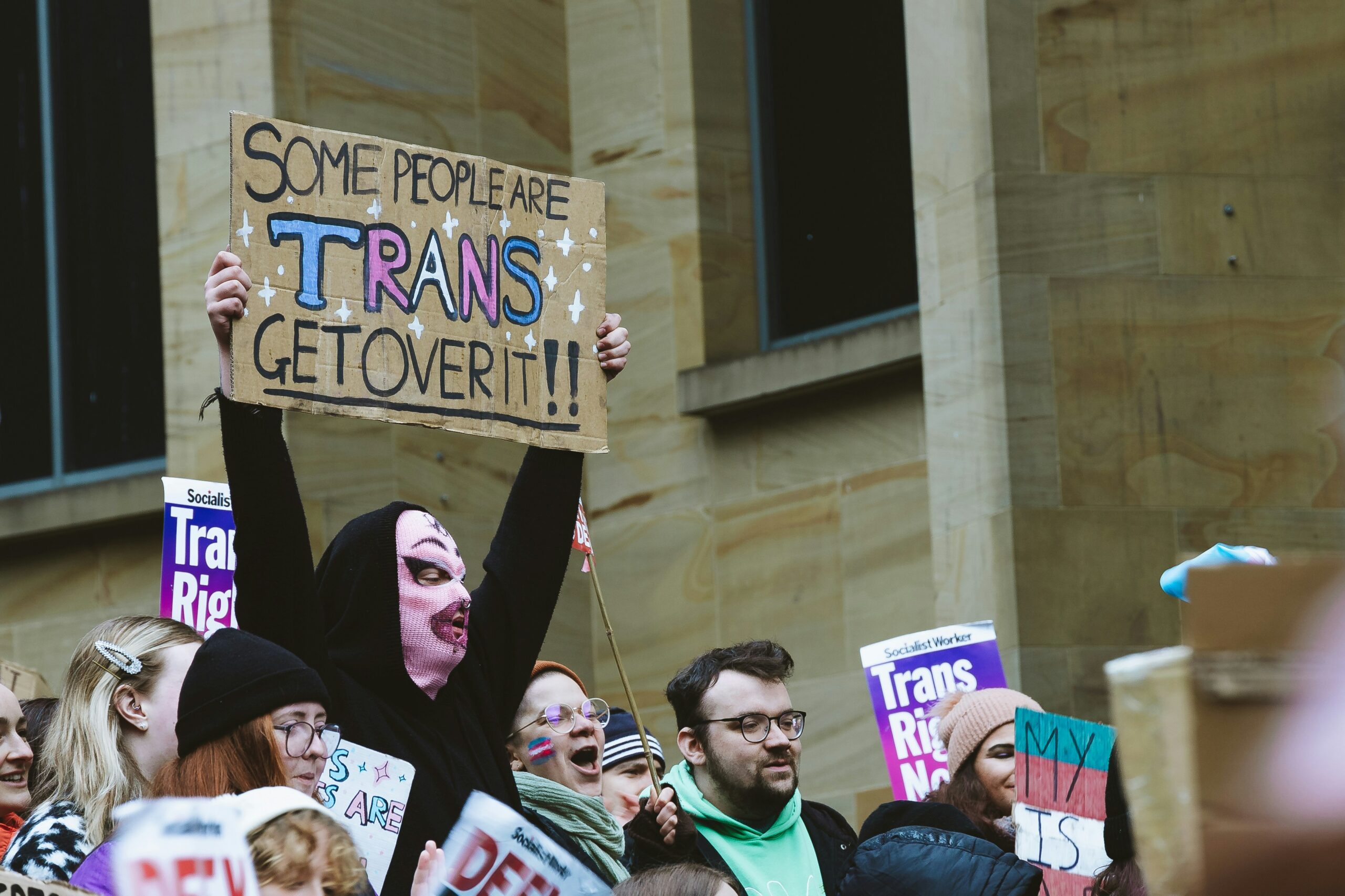 Photo of a masked person holding a sign at a protest.