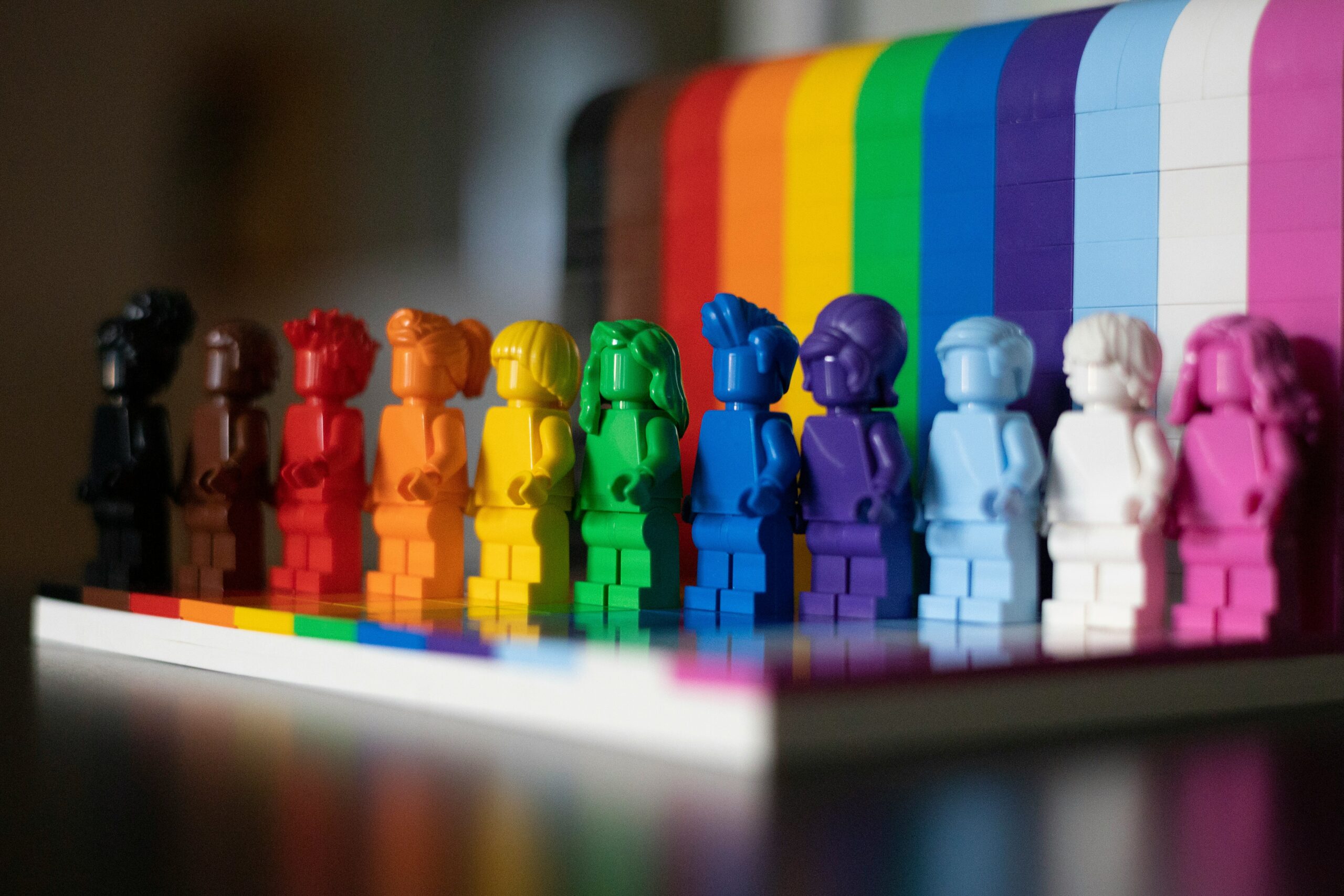 Photo of Lego People in rainbow colors in front of a rainbow.